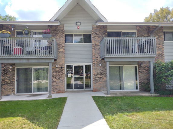Front view of a two-story building with balconies on the upper floor and sliding glass doors on the ground level.