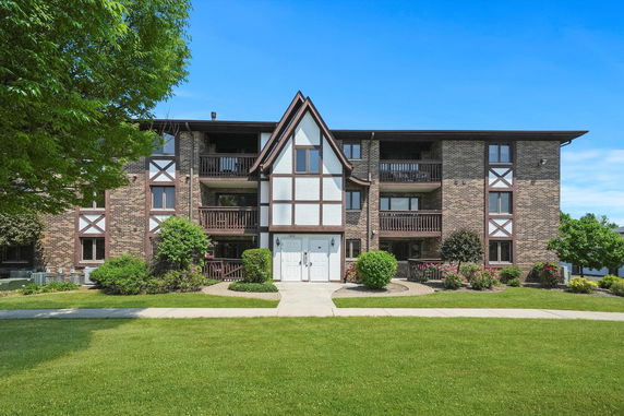 Front view of a multi-story apartment building with brick exterior and balconies.