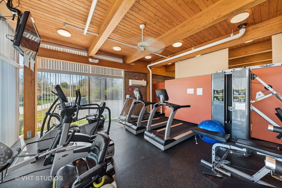 Indoor gym area with exercise equipment including treadmills, elliptical machines, and weights.