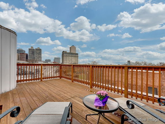 Rooftop with wooden deck and city skyline view.