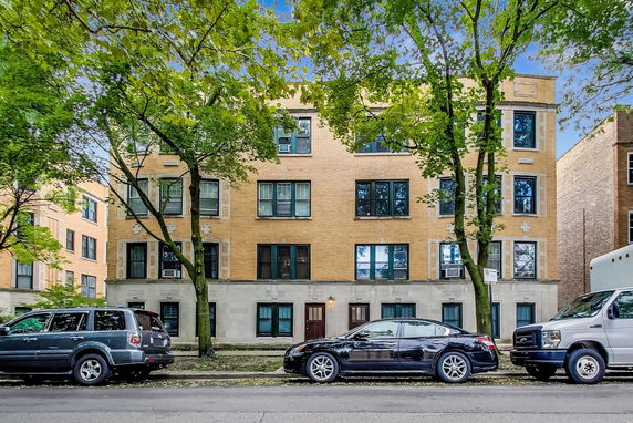 Front view of a multi-story brick apartment building with multiple windows.