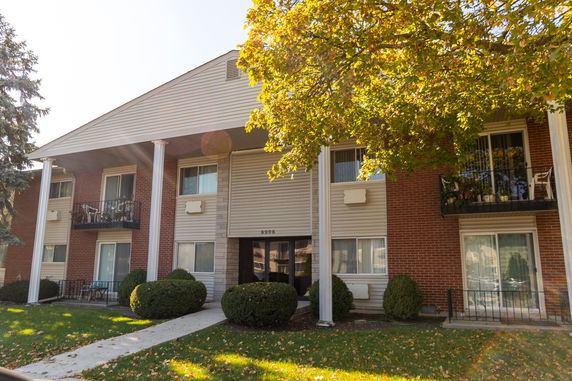 Front view of a two-story residential building with balconies and large white columns.