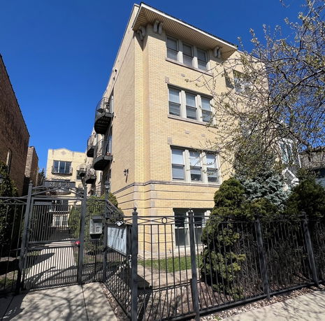 Front view of a multi-story apartment building with spiral fire escape.