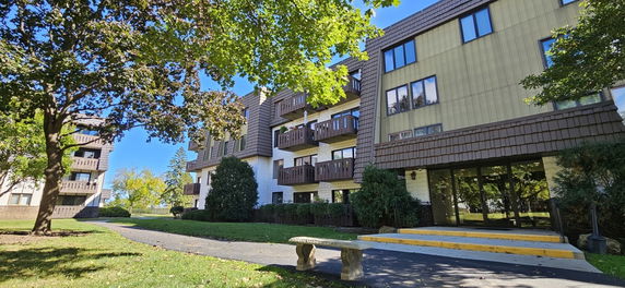 Front view of an apartment building with balconies and large windows.