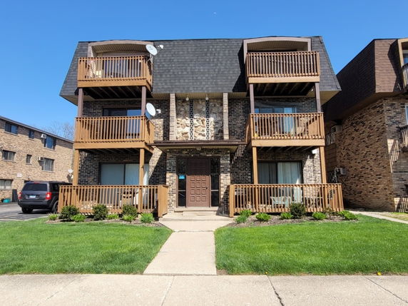 Front view of a multi-story building with wooden balconies.