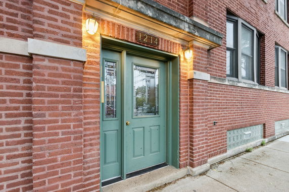 Front view of a building entrance with a green door and brick exterior.