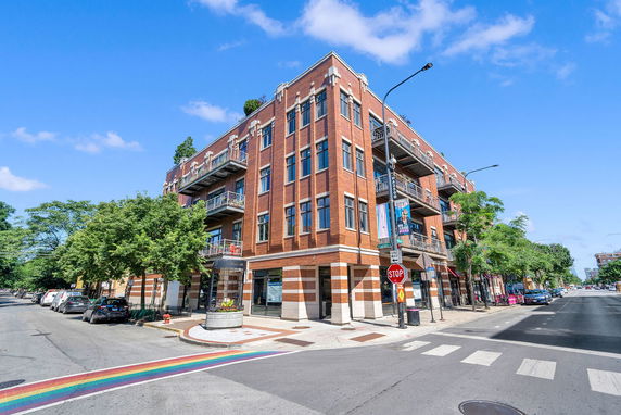 Front view of a multi-story brick building on a street corner.