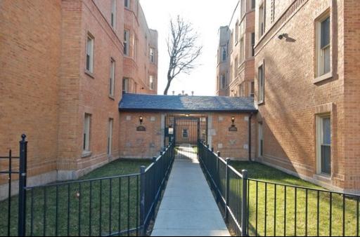 Entrance view of a multi-story brick apartment building with a pathway.