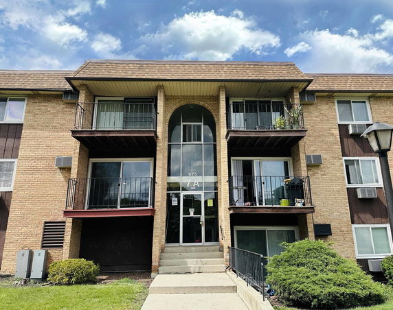 Front view of a multi-story brick apartment building with balconies.