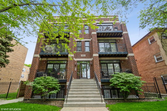 Front view of a multi-story brick apartment building with balconies.