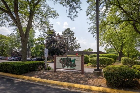 Entrance view of the Olive Trees condominium with parking area and signage.