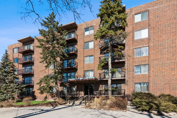 Front view of a multi-story brick apartment building with balconies.