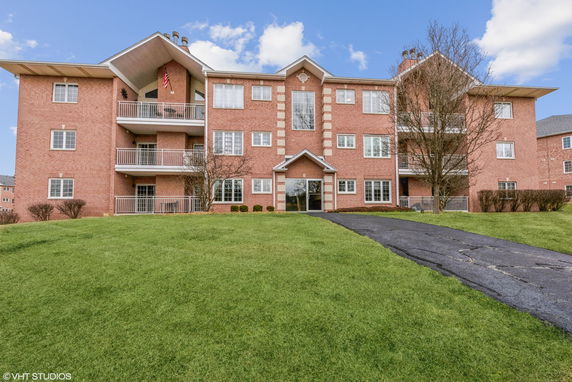 Front view of a three-story brick apartment building with balconies.