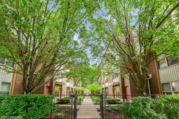 Front view of an apartment complex with trees and a gated entrance.