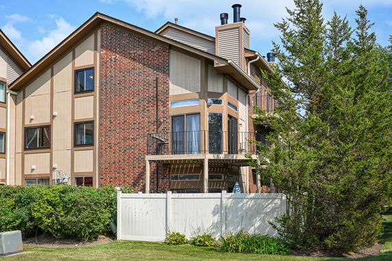 Front view of a multi-story house with a balcony and brick exterior.