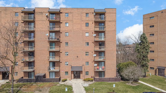 Front view of a multi-story brick apartment building with balconies.