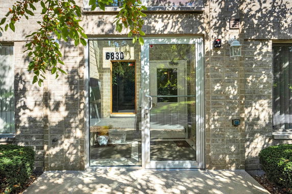 Front view of a building entrance with glass doors and brick exterior.