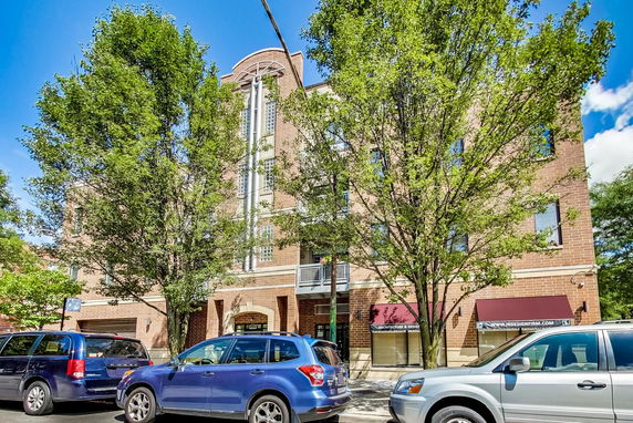 Front view of a multi-story building with large windows and brick facade.