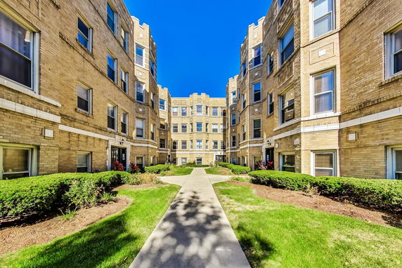 Front view of a multi-story apartment building with a courtyard entrance.