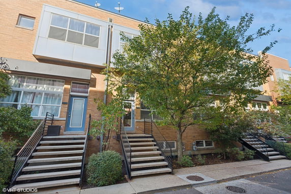 Front view of a multi-story brick townhouse with steps leading to the entrance.