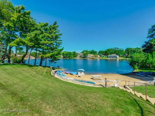 Panoramic view of a lake with surrounding trees and houses.