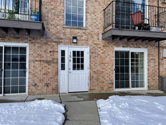 Front view of a brick apartment building with balconies and sliding glass doors.