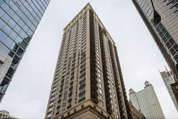 View looking up at a tall, multi-story building with numerous balconies.