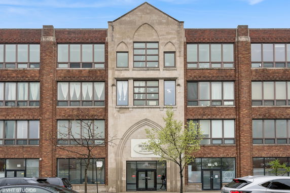 Front view of a multi-story brick building with large windows and an arched entrance.