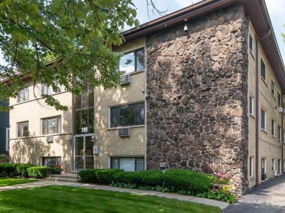 Front view of a multi-story apartment building with brick and stone exterior.