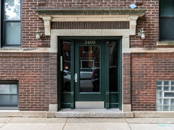 Front view of a building with a brick exterior and green entrance door.