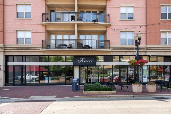 Front view of a multi-story building with retail space on the ground floor and balconies on the upper levels.