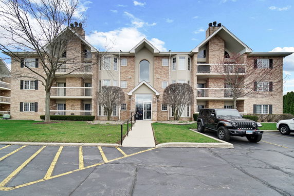 Front view of a multi-story apartment building with balconies and brick facade.