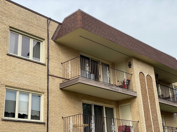 Front view of a multi-story brick apartment building with balconies.
