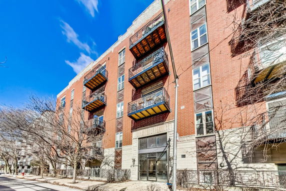 Front view of a multi-story brick apartment building with balconies.