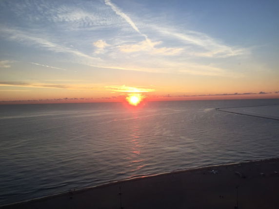 Wide-angle view of the ocean at sunset with a horizon line.