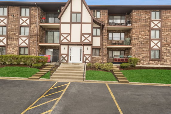 Front view of a three-story apartment building with brick facade and balconies.