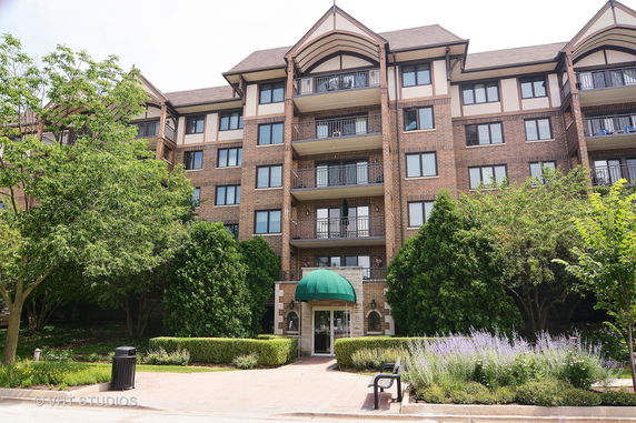 Front view of a multi-story residential building with balconies and a green awning at the entrance.