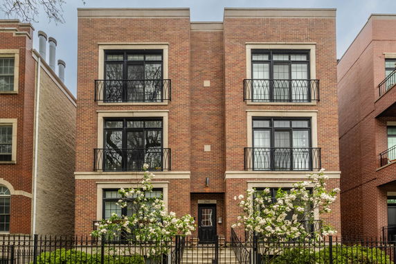 Front view of a multi-story brick building with large windows and decorative balconies.
