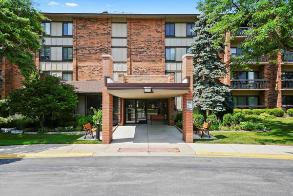 Front view of a multi-story brick apartment building with an entrance canopy.