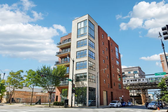 Front view of a multi-story brick building with balconies on a street corner.