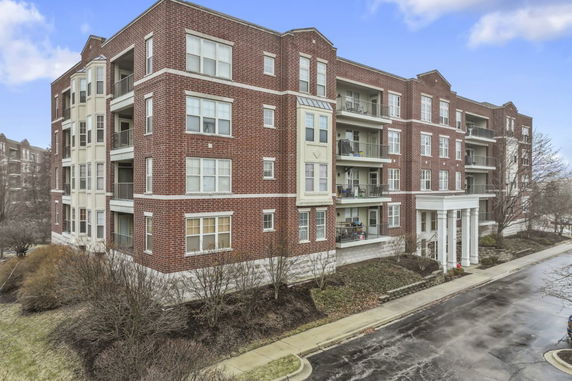 Front view of a multi-story brick apartment building with balconies and large windows.