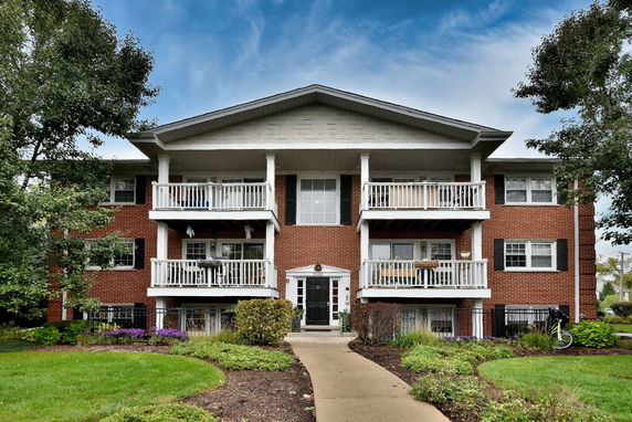 Front view of a three-story brick building with white railings and symmetrical balconies.