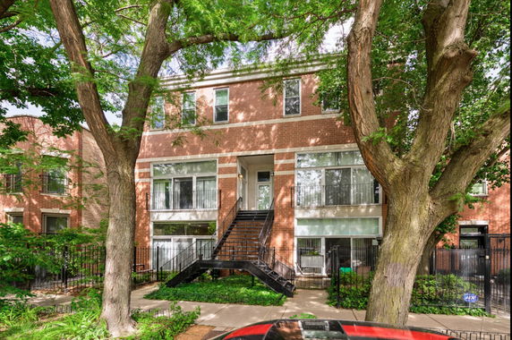 Front view of a multi-story brick building with stairs leading to the entrance.