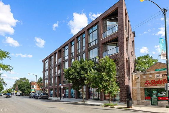 Front view of a multi-story brick building with large windows and balcony sections.