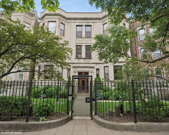Front view of a large three-story building with ornate architectural details and a gated entrance.