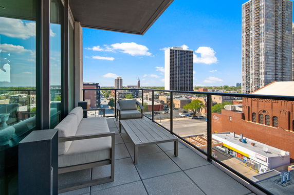 View of city buildings from a balcony with seating area.