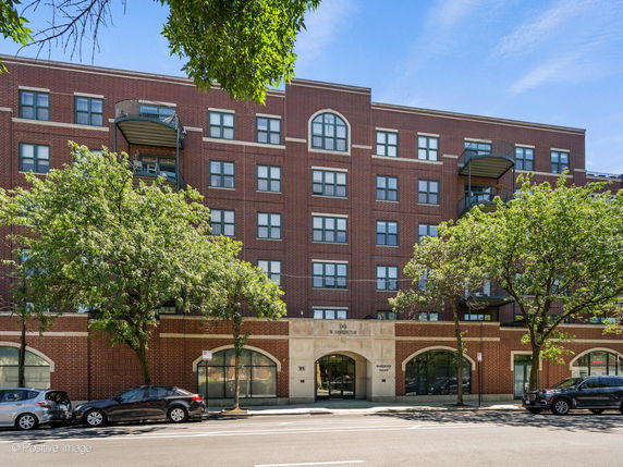 Front view of a multi-story brick building with arched entryways and balconies.