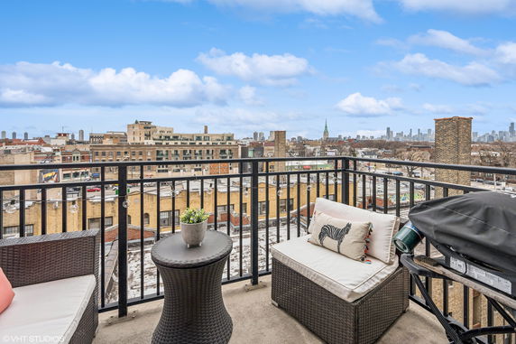Outdoor balcony with seating and a view of city buildings.