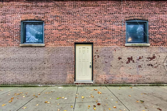 Front view of a brick building with a single door and two windows.