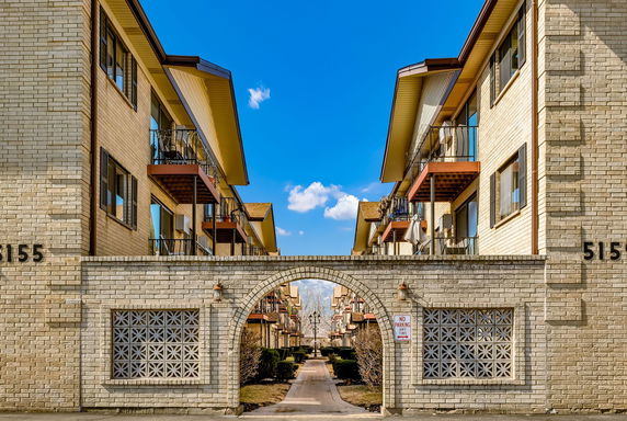 Front view of a multi-story apartment building with balconies and an archway entrance.